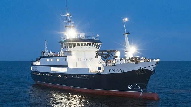 A Russian trawler under lights at sea at night